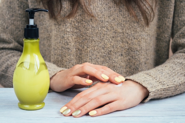 Les mains des femmes avec manucure jaune appliqué la crème pour les mains