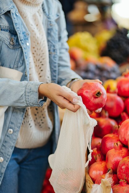 Les mains des femmes mettent les fruits et légumes dans un sac de produits en coton au marché alimentaire. Sac écologique réutilisable pour faire du shopping. Mode de vie durable. Concept écologique.