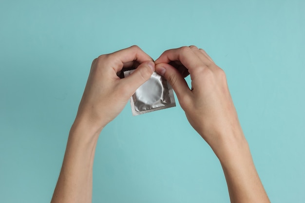 Les mains des femmes ouvrent un préservatif sur papier bleu