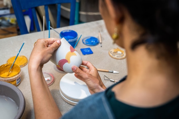 Les mains des femmes peignant un objet de poterie