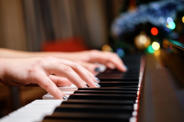 Les mains des femmes sur le piano, gros plan, beau bokeh en arrière-plan