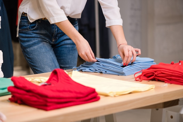 Les mains des femmes plient des chemises bleues au magasin de vêtements