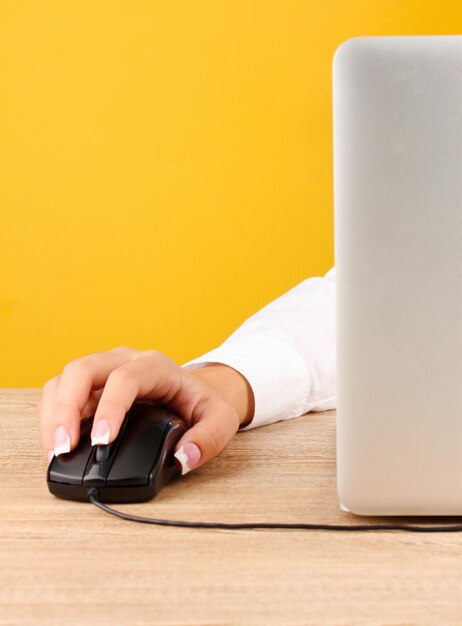 Photo des mains de femmes poussant des touches de souris pc sur fond jaune en gros plan