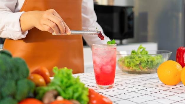 Mains de femmes préparant un mocktail en mettant du mûrier sucré dans un verre