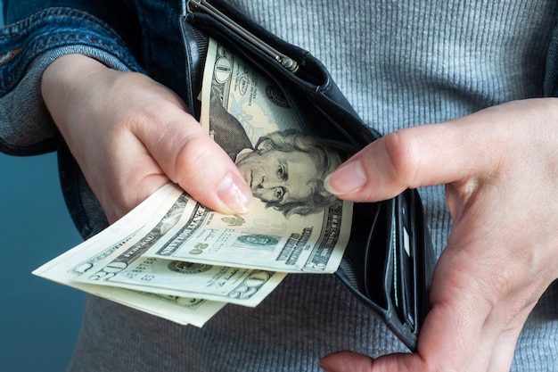 Les mains des femmes retirent de l'argent de leur portefeuille.