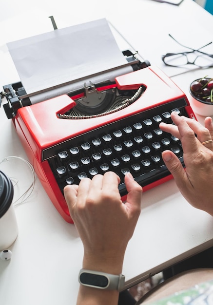 Les mains des femmes tapent sur une machine à écrire vintage rouge vif