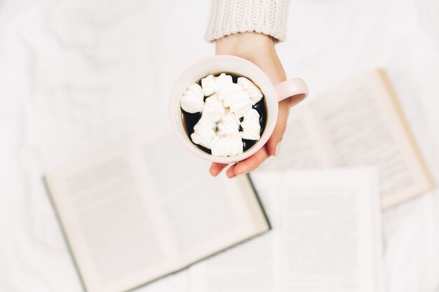 Mains de femmes avec une tasse de café et des livres. Photo minimaliste élégante. Vue de dessus.