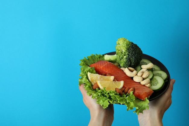 Les mains des femmes tiennent des aliments sains sur fond bleu