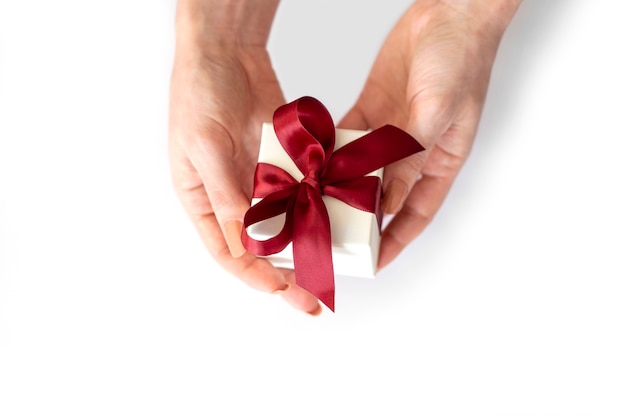 Les Mains Des Femmes Tiennent Une Boîte Cadeau Blanche Avec Un Arc Rouge Sur Fond Blanc