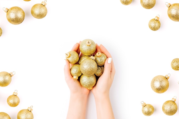 Les mains des femmes tiennent des boules de Noël dorées