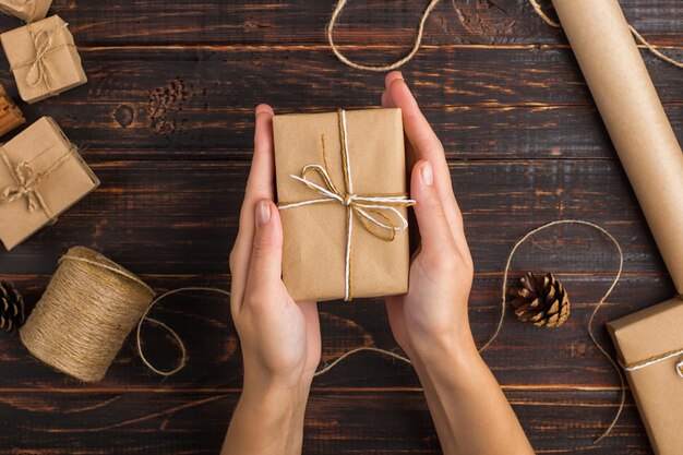 Les mains des femmes tiennent un cadeau de papier kraft.