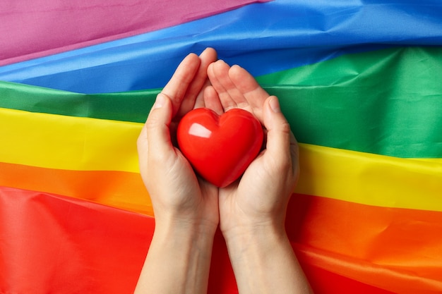 Les mains des femmes tiennent le coeur sur le drapeau LGBT, vue du dessus