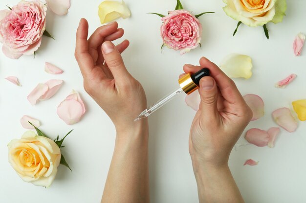 Les mains des femmes tiennent la pipette avec de l'huile essentielle de rose