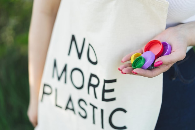 Photo les mains des femmes tiennent une poignée de couvercles en plastique multicolores concept de pollution de l'environnement