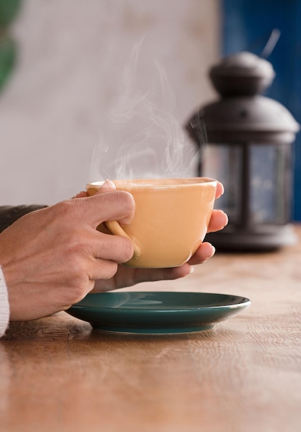 Les mains des femmes tiennent une tasse jaune avec du café Focus sur la tasse