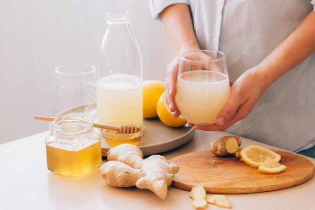 Les mains des femmes tiennent un verre avec une boisson à base de miel de gingembre et de citron antioxydant fraîchement préparé