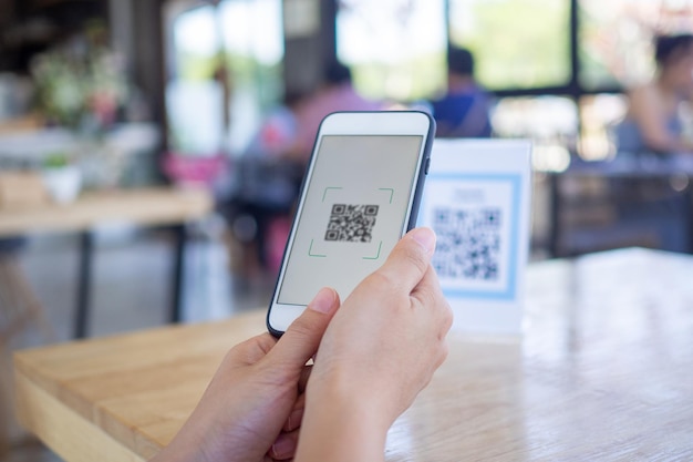 Photo les mains des femmes utilisent le téléphone pour scanner le code qr pour sélectionner le menu alimentaire. scannez pour obtenir des remises ou payer pour de la nourriture. le concept d'utiliser un téléphone pour transférer de l'argent ou payer de l'argent en ligne sans espèces.