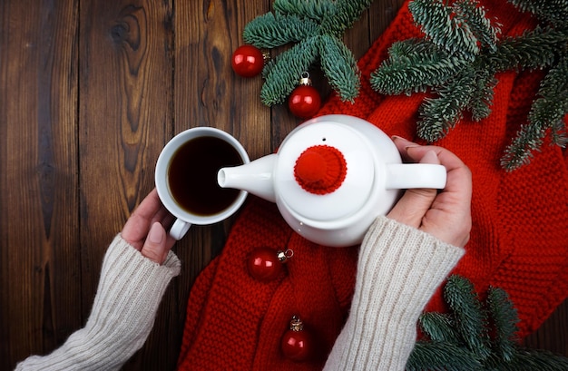 Les mains des femmes versent le thé d'une théière dans une tasse