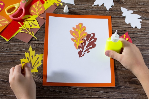 Mains avec des feuilles de papier coloré sur table en bois