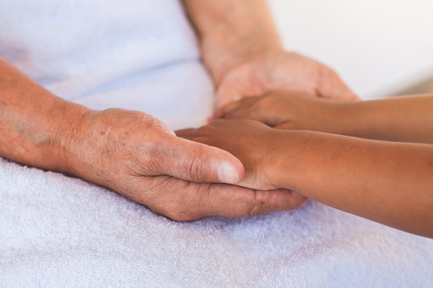 Mains de fille asiatique enfant tenant mains de grands-parents âgés peau ridée avec soin et amour