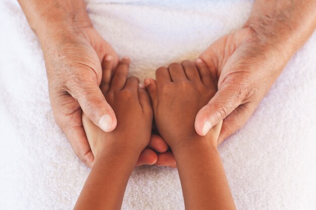 Mains de fille asiatique enfant tenant mains de grands-parents âgés peau ridée avec soin et amour