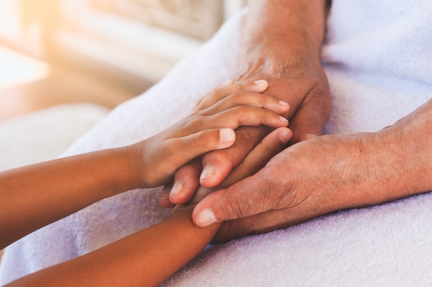 Mains de fille asiatique enfant tenant mains de grands-parents âgés peau ridée avec soin et amour