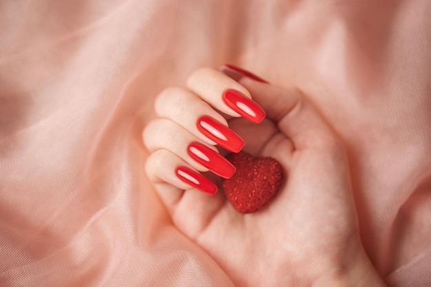 Mains de fille avec manucure rouge et coeur décoratif