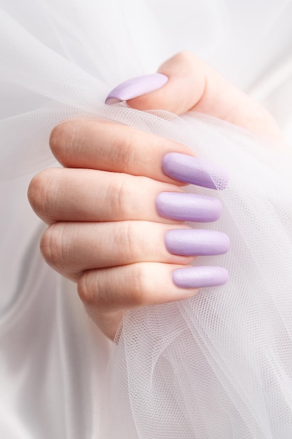 Les mains de la fille avec une manucure violette douce