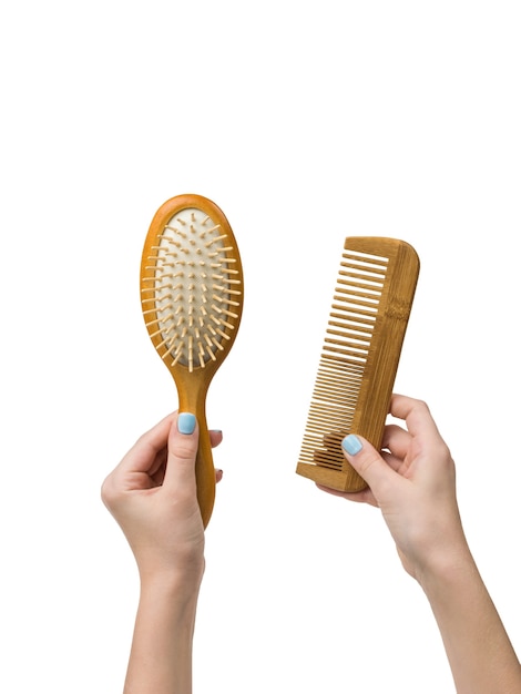 Les mains d'une fille avec des peignes en bois isolés sur fond blanc. Outils pour le soin des cheveux.