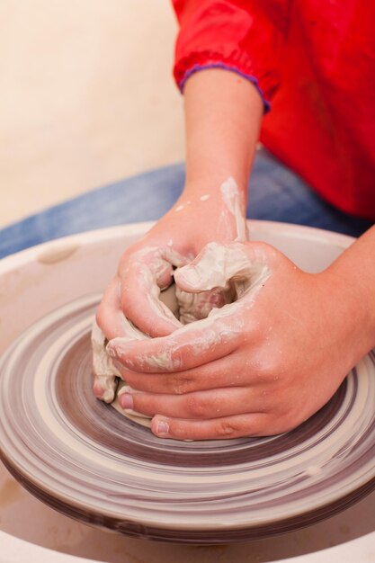 Mains de fille qui fait de la poterie à partir d'argile blanche sur un tour de potier