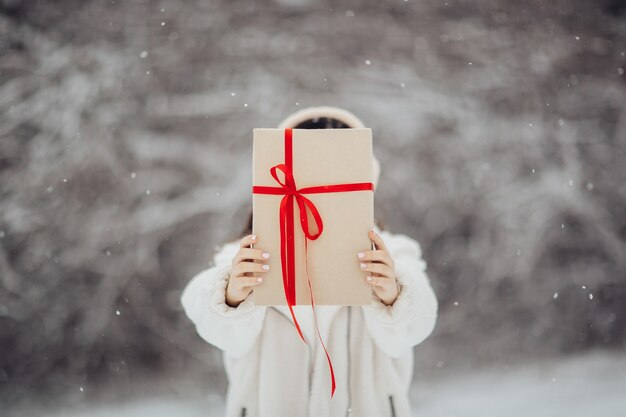 Mains de fille tenir la boîte-cadeau avec ruban rouge. Concept de vacances d'hiver. La Saint-Valentin.