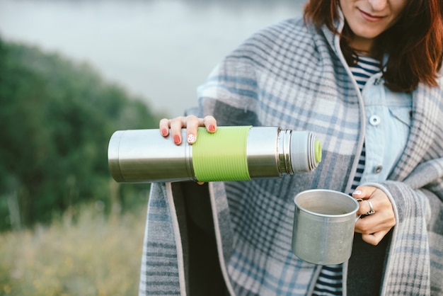 Photo mains de fille avec thermos et mug