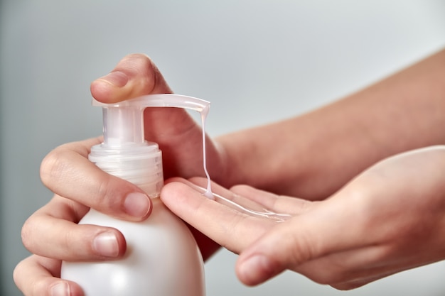 Mains de fille en utilisant un désinfectant pour les mains ou du savon liquide. Prévention des maladies virales