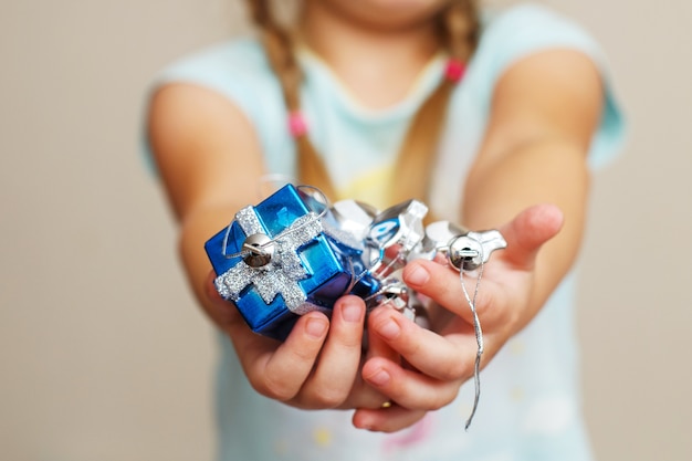 Les mains des filles tiennent la tenue d'un jouet de noël une boîte-cadeau bleue