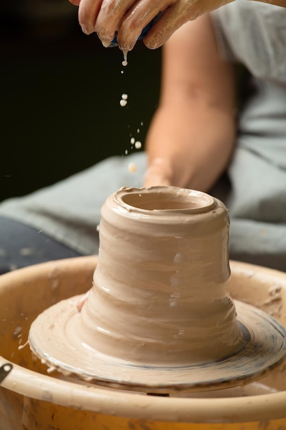 Les mains des filles travaillent sur une roue de potier créant un vase ou un bol en céramique Poterie de créativité