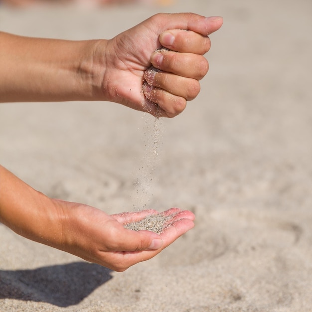 Mains filles verser du sable d'une main à l'autre Gros plan jeune femme avec du sable dans ses mains