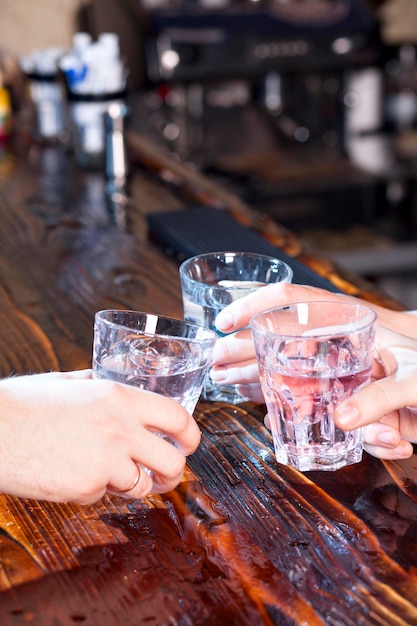 Les mains font des acclamations avec des verres de vodka