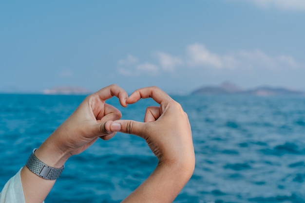 Photo les mains en forme de coeur contre la mer. mains formant une forme de coeur.