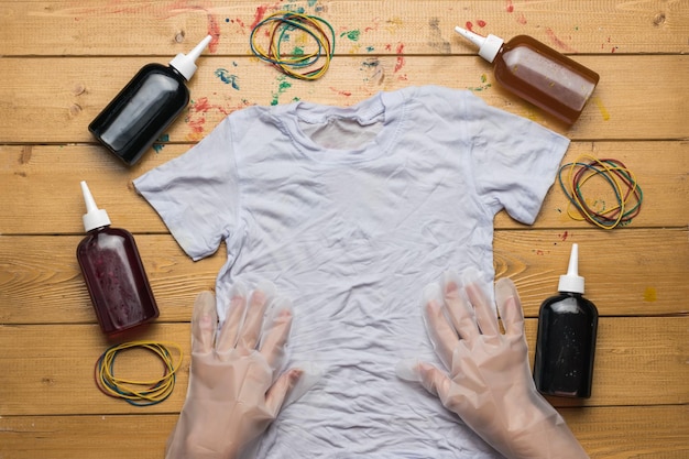 Les mains gantées des femmes avant de teindre les t-shirts tie dye. Le processus de peinture dans le style de teinture de cravate. Mise à plat.