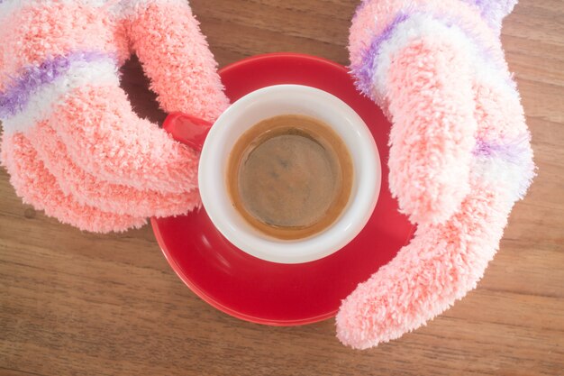 Mains gantées tenant une tasse de café