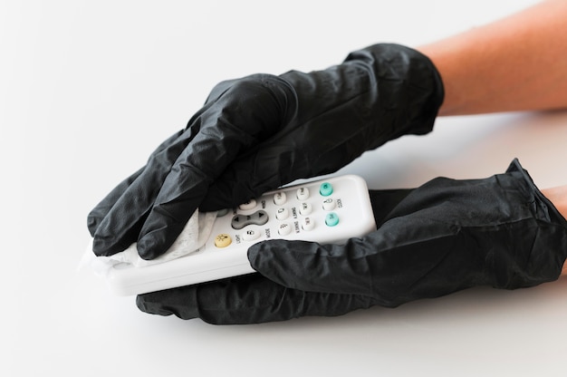 Mains avec des gants chirurgicaux désinfectant la télécommande