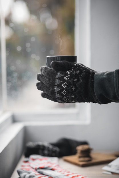 Mains avec des gants d'hiver tenant une tasse de café