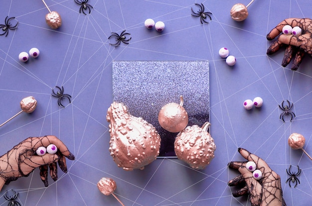 Mains en gants en maille noire imitant de grosses araignées aux yeux chocolat. Un plat Halloween fantasmagorique créatif était en violet, rose métallique et noir avec des citrouilles et des araignées.