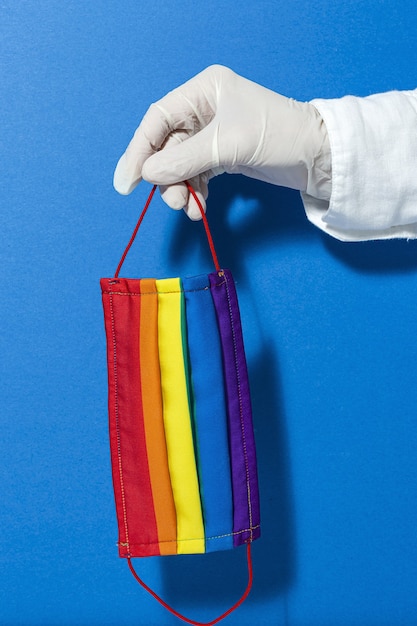 Mains avec des gants montrant des masques LGBT de mode et de conception faits maison pour la protection du covid-19