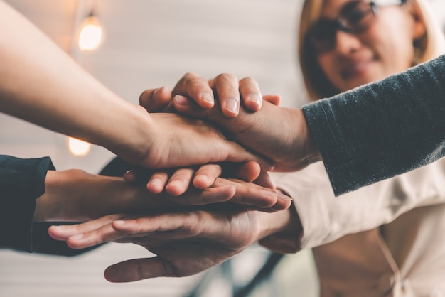 Les mains des gens d'affaires se réunissent dans une pile de mains pour symboliser la collaboration, le travail d'équipe pour atteindre les objectifs et le succès.