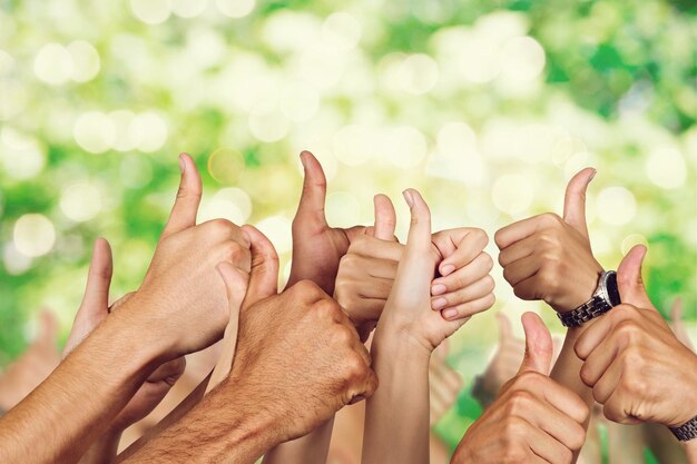 Mains gesticulant pouces vers le haut sur fond vert