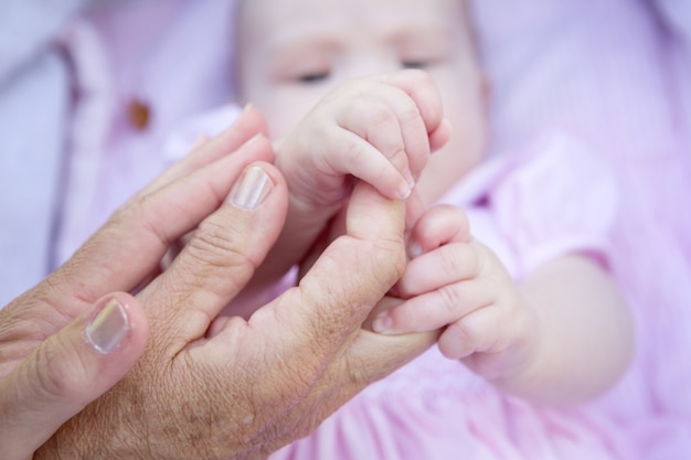 Mains de grand-mère tenant les mains de bébé