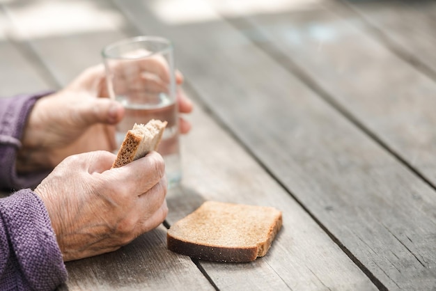Les mains de grand-mère tiennent du pain et de l'eau le concept de vieillesse pauvre