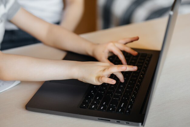 Mains d'un gros plan enfant sur le clavier de l'ordinateur portable. Apprentissage à distance. Reste à la maison.