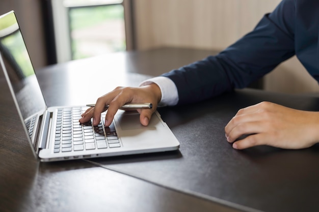 Mains d&#39;homme d&#39;affaires à l&#39;aide d&#39;un ordinateur portable au bureau dans le bureau